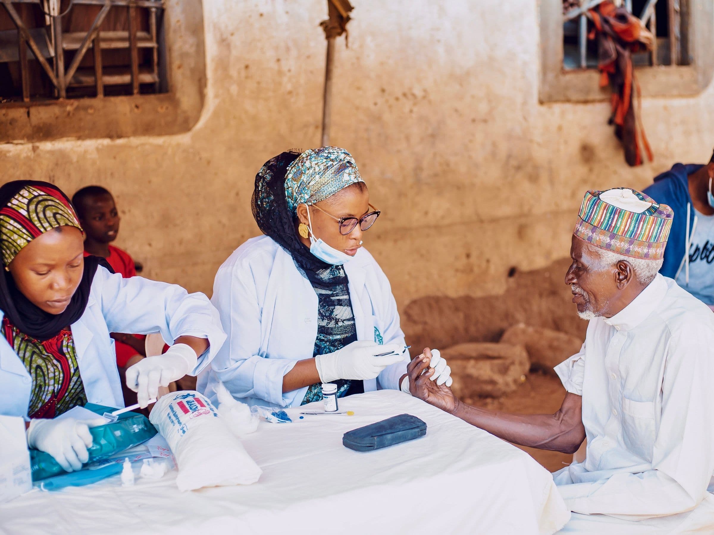 health workers collecting health data with a community member during an outreach program